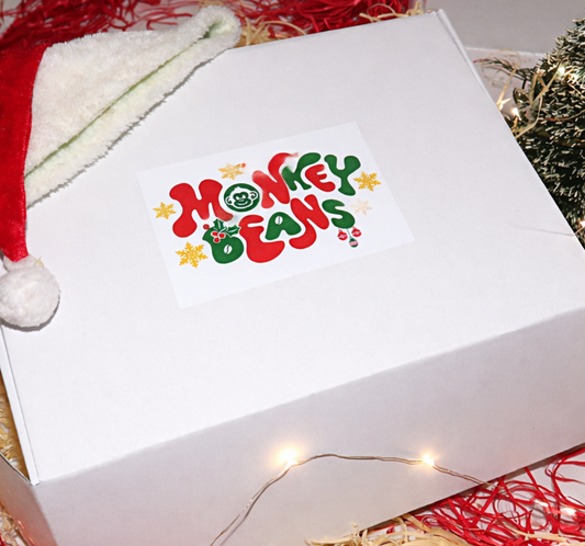 White box with 'Monkey Beans' logo, red and white hat, and Christmas decorations on a red and gold straw-like material.